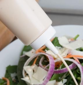 Salad dressing poured from a clear squeeze bottle