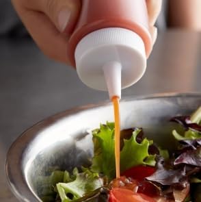 Close-up of a squeeze bottle nozzle dispensing onto food