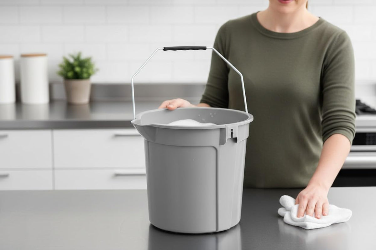 Metal-handled gray bucket beside a person cleaning a countertop