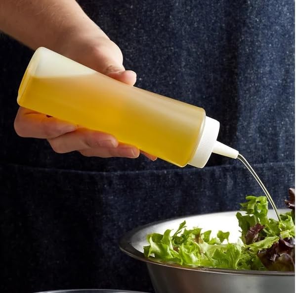 Sauce being poured from a squeeze bottle over greens
